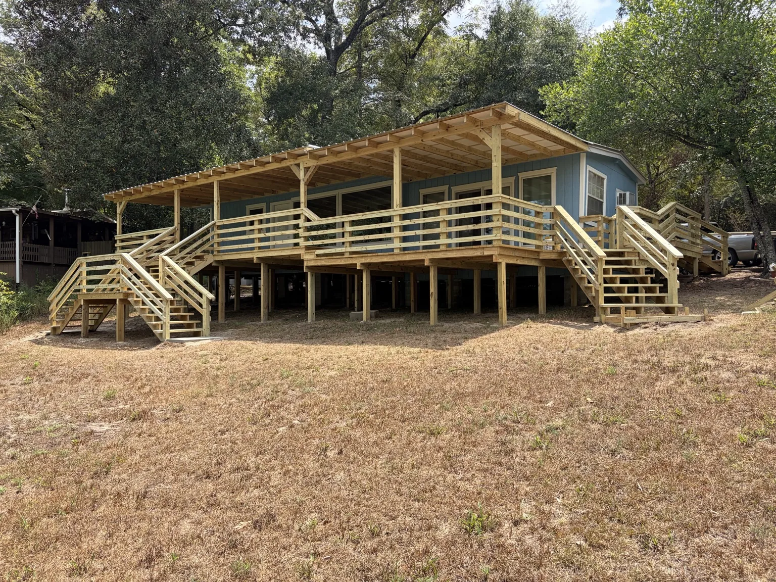 Finished blue house with large deck and covered porch by Davco Designz